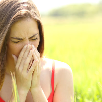 44652575 - woman with allergy coughing in a green color field in summer